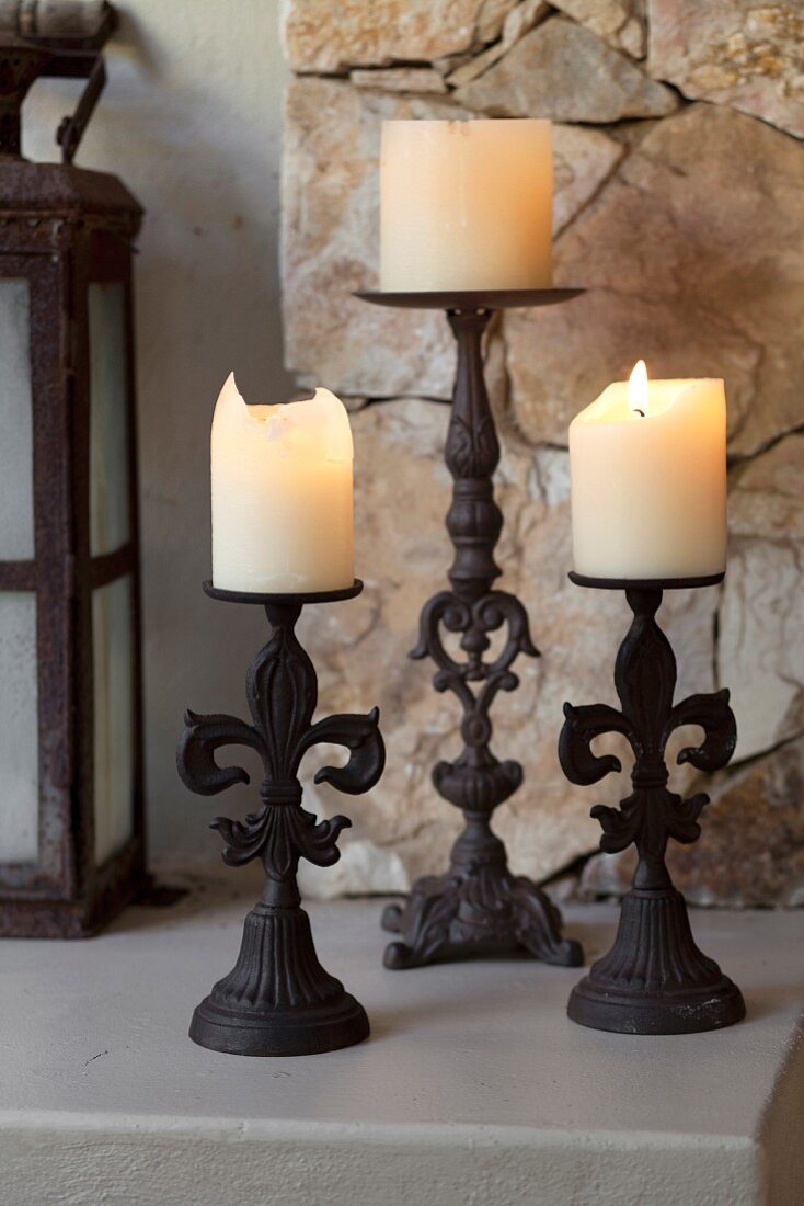 Lit pillar candles on three wrought iron candle sticks