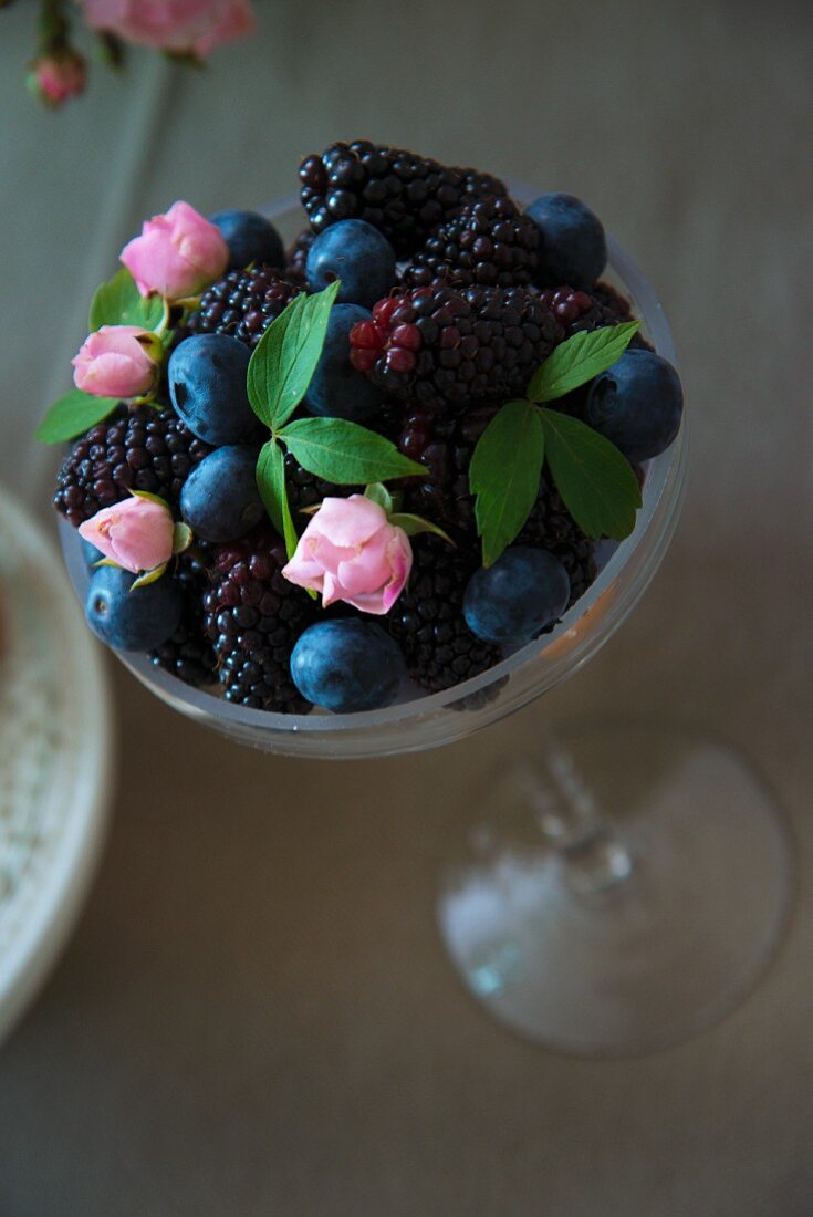 Beeren mit kleinen Rosenblüten in einem Dessertglas