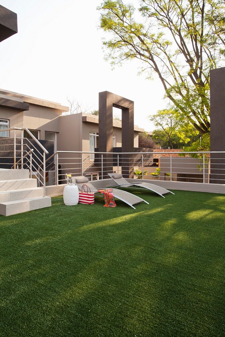 Artificial lawn, sun loungers and stainless steel balustrade on roof terrace