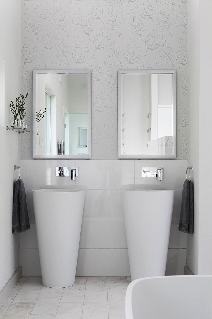 Zwei Designer-Standwaschbecken vor Spiegel, an Wand zartes, grafisches Blumenmuster