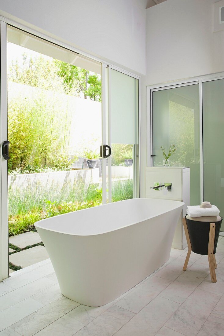 Freistehende Badewanne in modernem Bad, seitlich offene Terrassen Schiebetüren