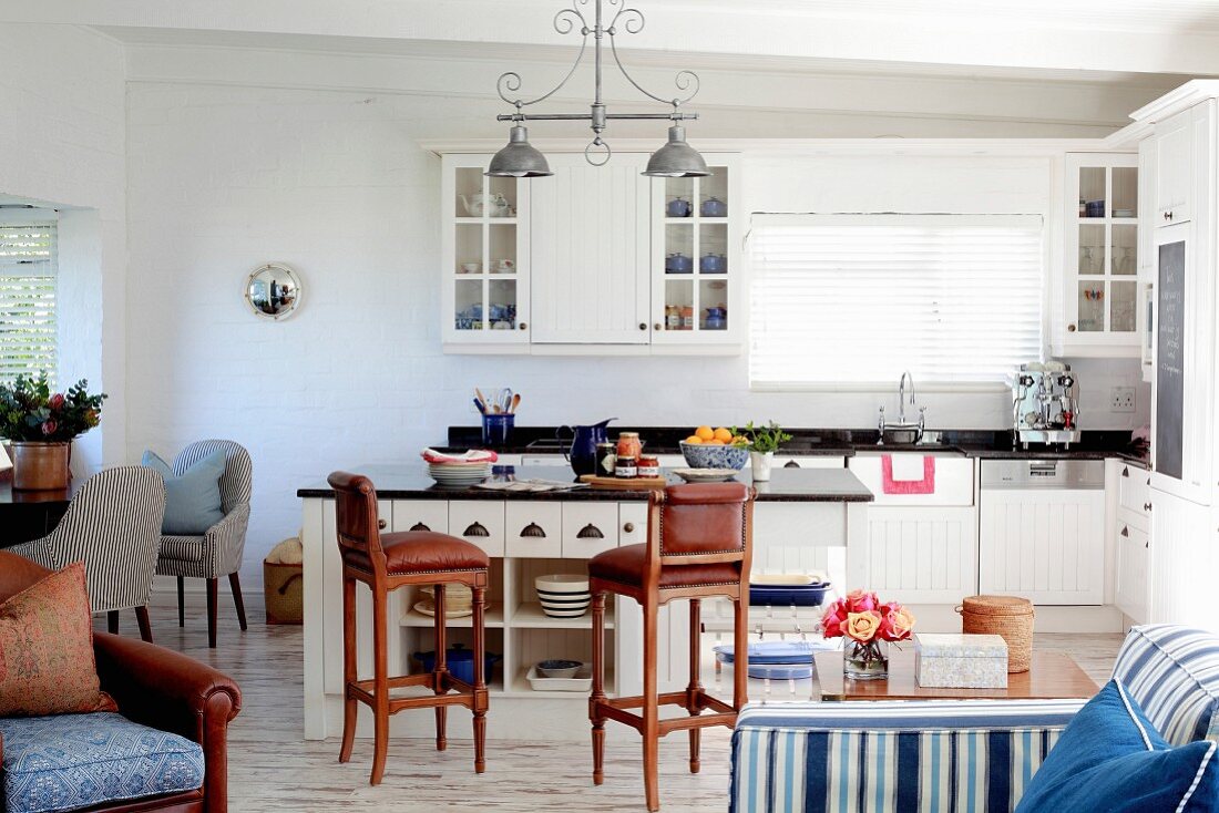 Bright country-house kitchen with island counter, brown bar stools and blue accessories