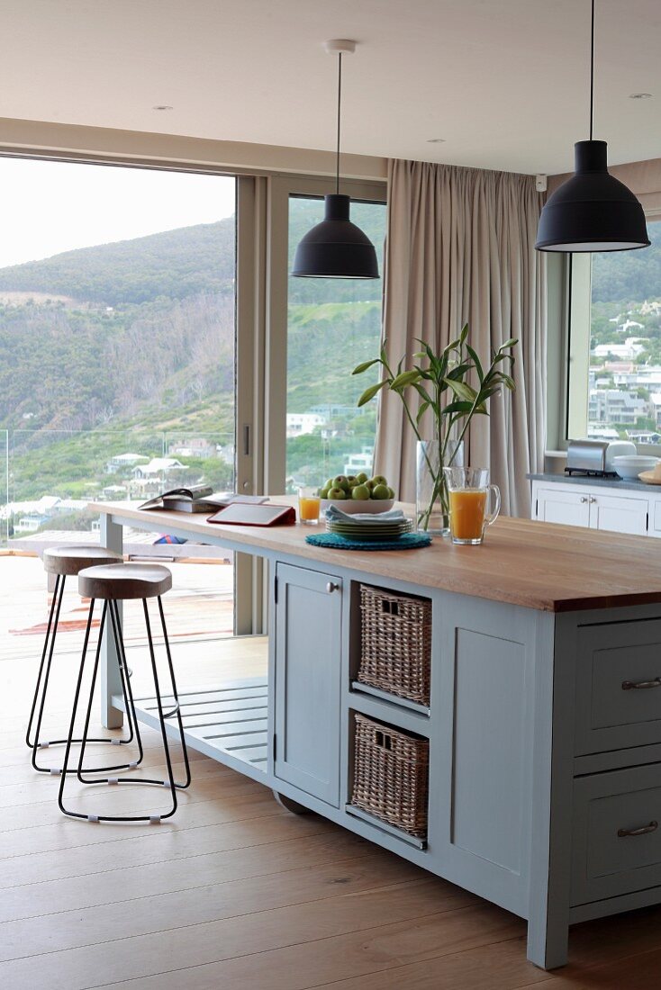 Kücheninsel im Landhausstil mit zwei Barhockern und Blick durch große Fensterfronten