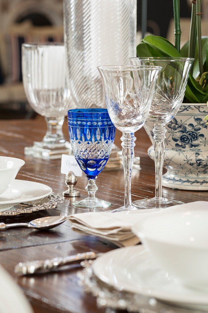 Ausschnitt aus gedecktem Tisch mit Kristallgläsern, weißem Geschirr und Silberbesteck