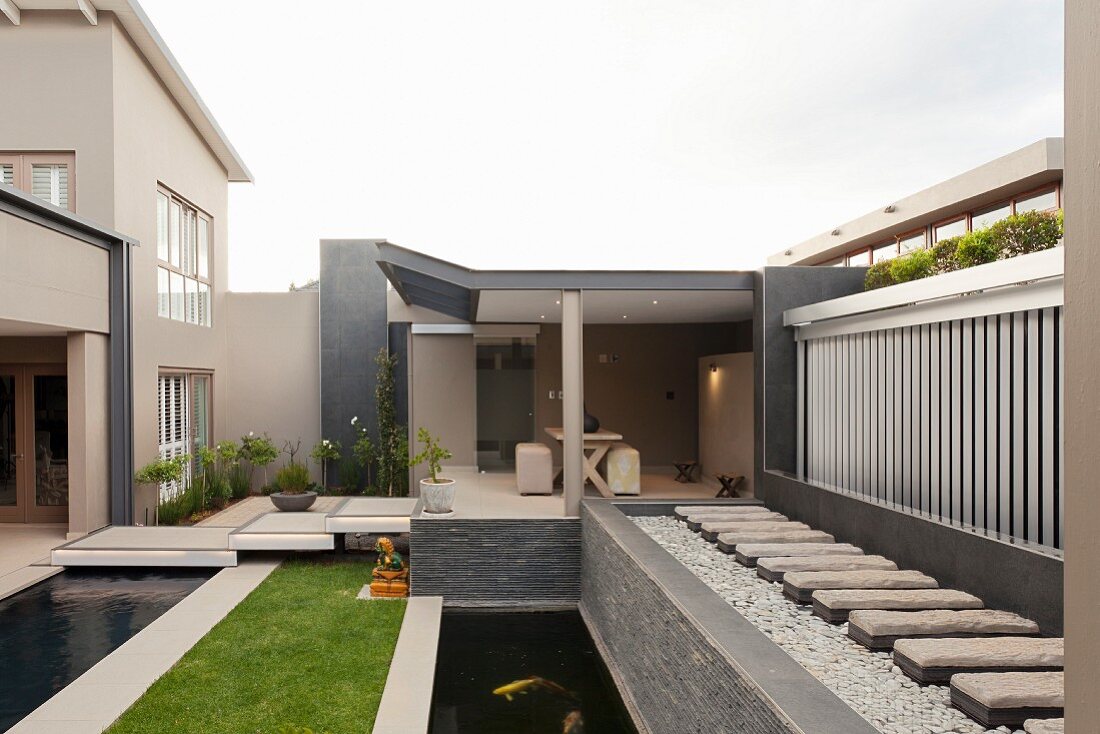 Modern designer garden with linear configuration of pool, lawn, pond and seating area