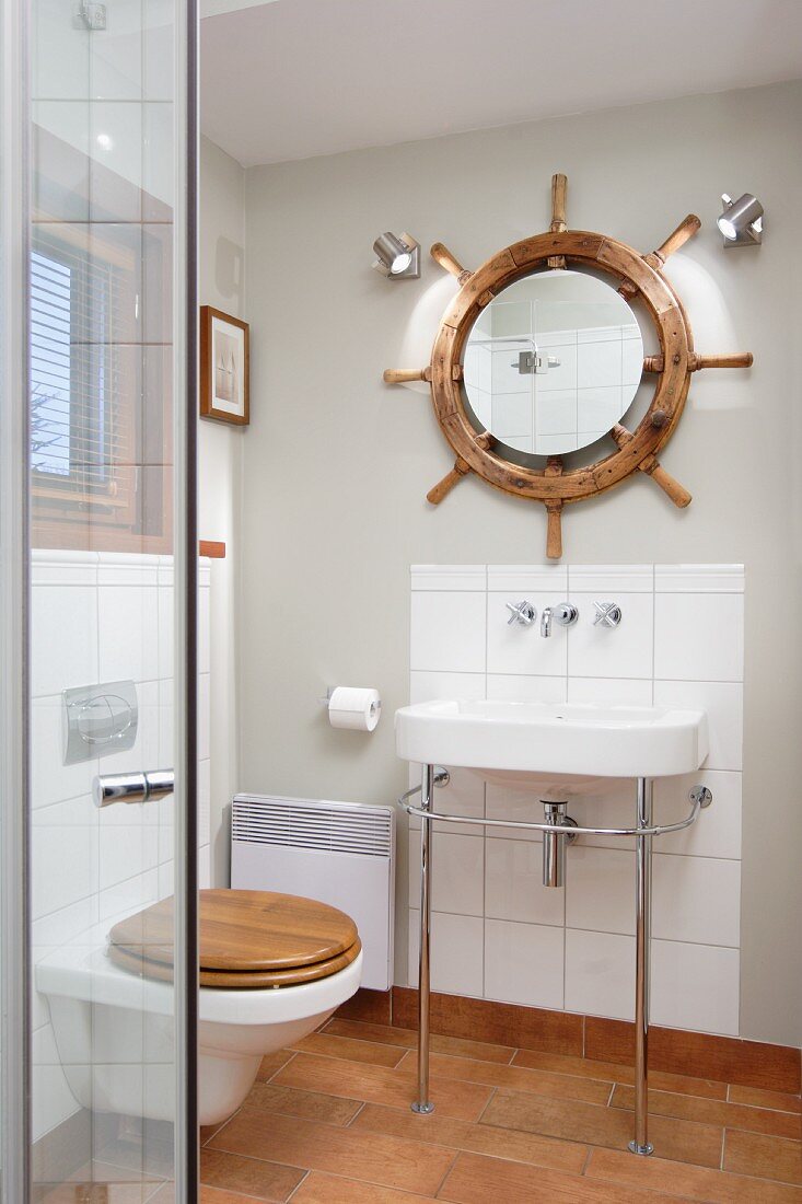 Waschtisch mit Metallgestell vor kleiner Fliesenfläche unter Spiegel mit Steuerrad Deko in modernem Bad