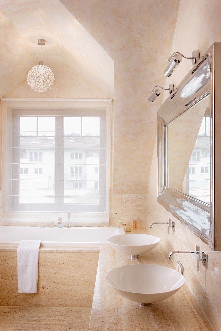 Bathroom with pale beige stone tiles, marbled ceiling in matching shade and twin sinks below elegant mirror