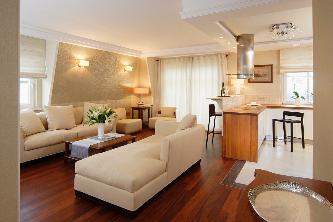 Classic, cream sofa set on exotic wood parquet floor and open-plan kitchen area in background in traditional interior