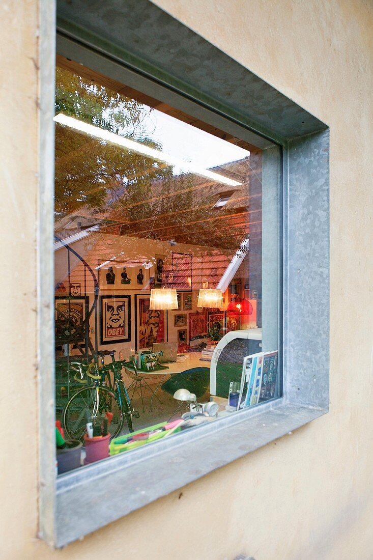 Blick durch Fenster mit Rahmen aus verzinktem Stahl in Wohnraum mit Kunstsammlung und Fahrrad
