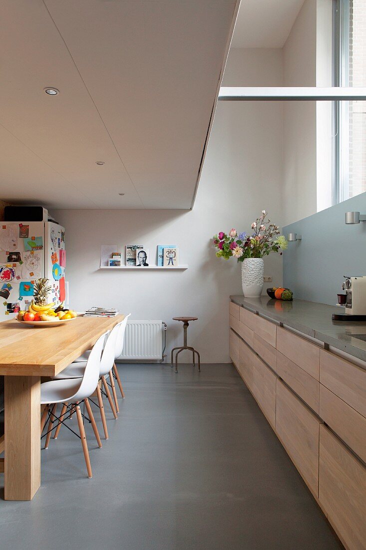 Langgestreckte Küchenzeile mit hellen Holzfronten in Wohnküche mit Galerie