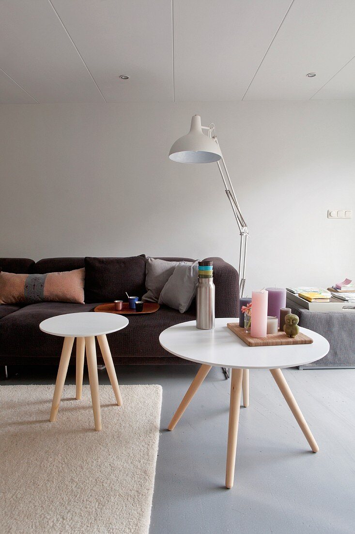 Round, white side tables and brown sofa in living room