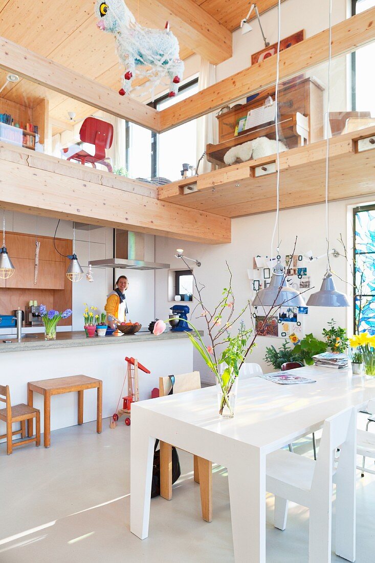 Kitchen and dining area in open-plan interior below wooden gallery