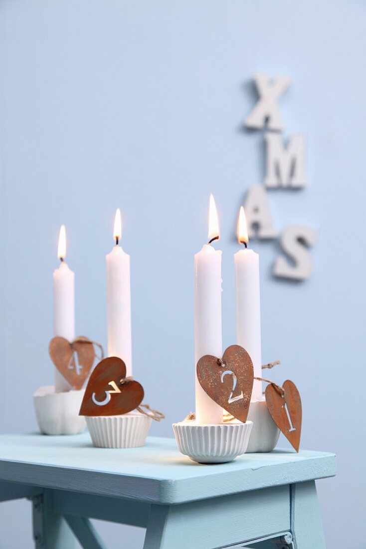 Advent candle holders made from silicone muffin cases, plaster and numbers on heart-shaped pendants