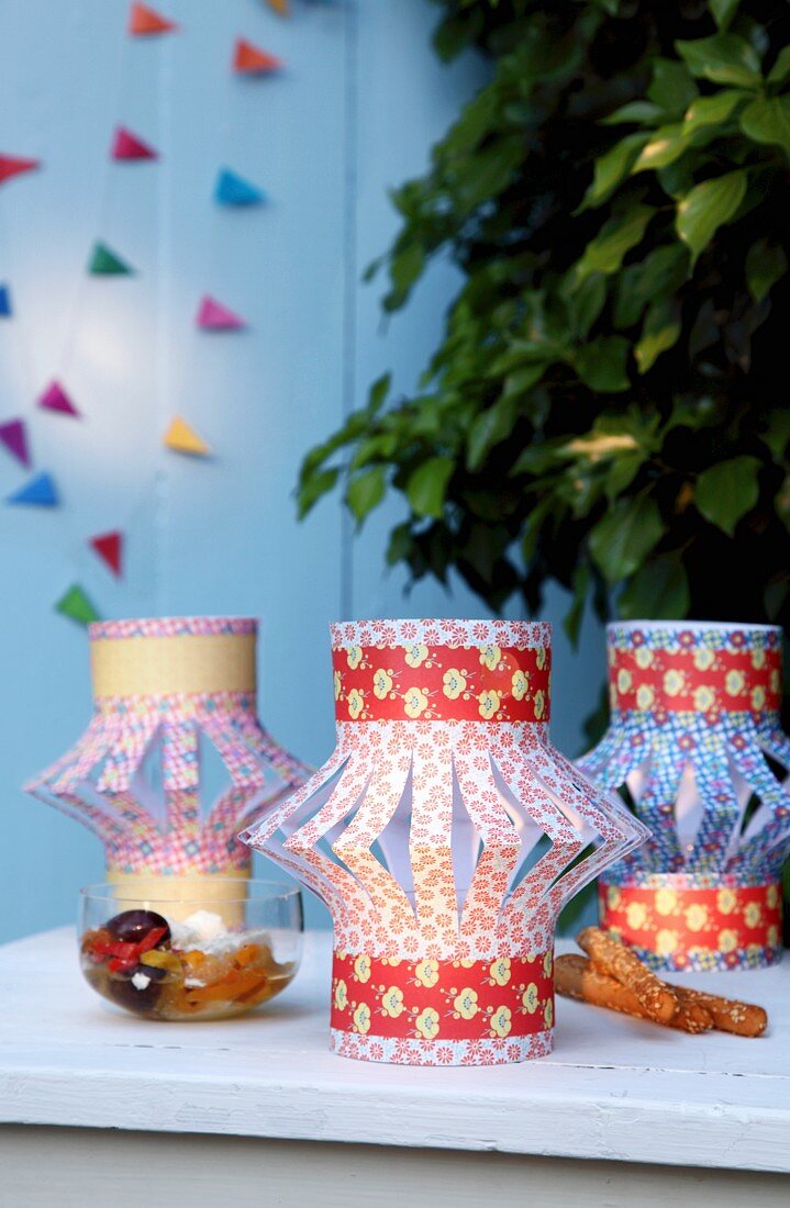Lampionartige Schirmchen für Teelichter aus gefaltetem und beschnittenem Papier mit bunten Mustern