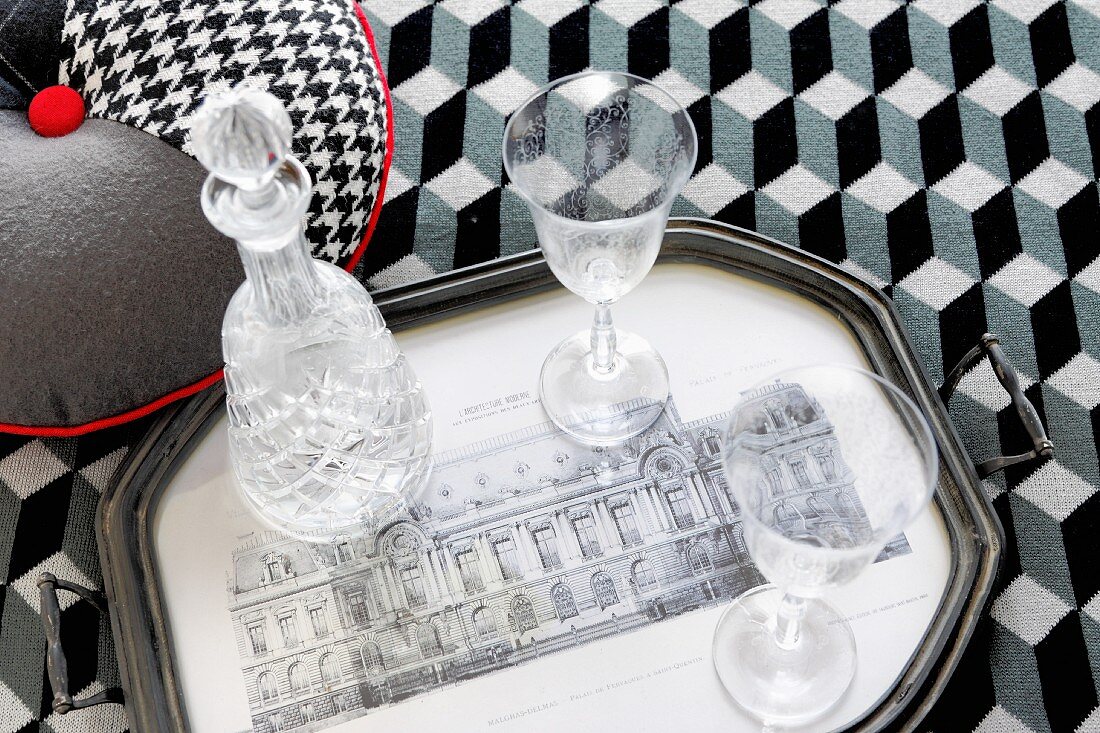 Tablett mit Gläsern und Kristallkaraffe auf Decke mit Illusionsgrafik