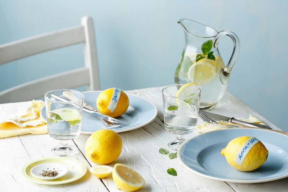 Gedeckter Tisch mit Zitronen und Zitronenwasser