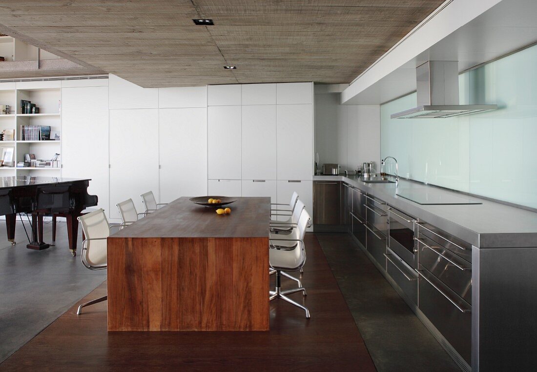 Minimalistischer Esstisch aus Massivholz und Klassiker Drehstühle in offener Küche mit Betondecke