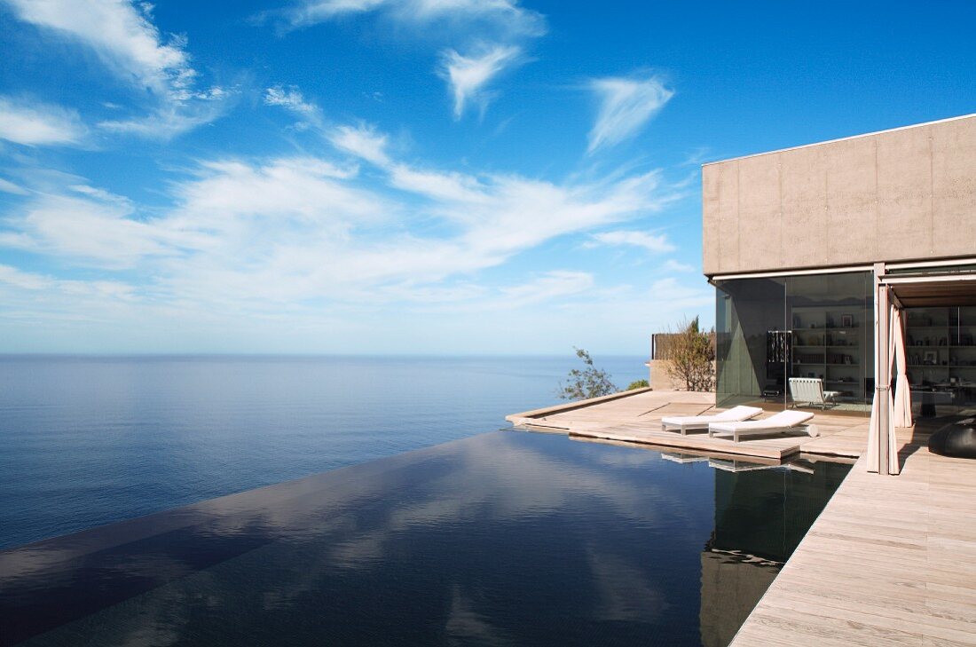 Zeitgenössisches Wohnhaus mit umlaufender Terrasse, seitlich Infinity Pool mit nahtlosem Blick auf das Meer