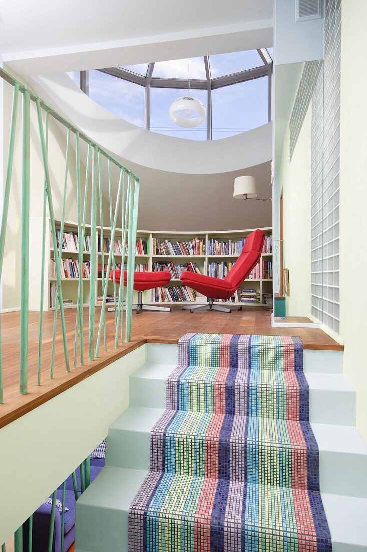 Striped stair runner on masonry staircase, open-plan attic room with red easy chair and footstool under glass dome