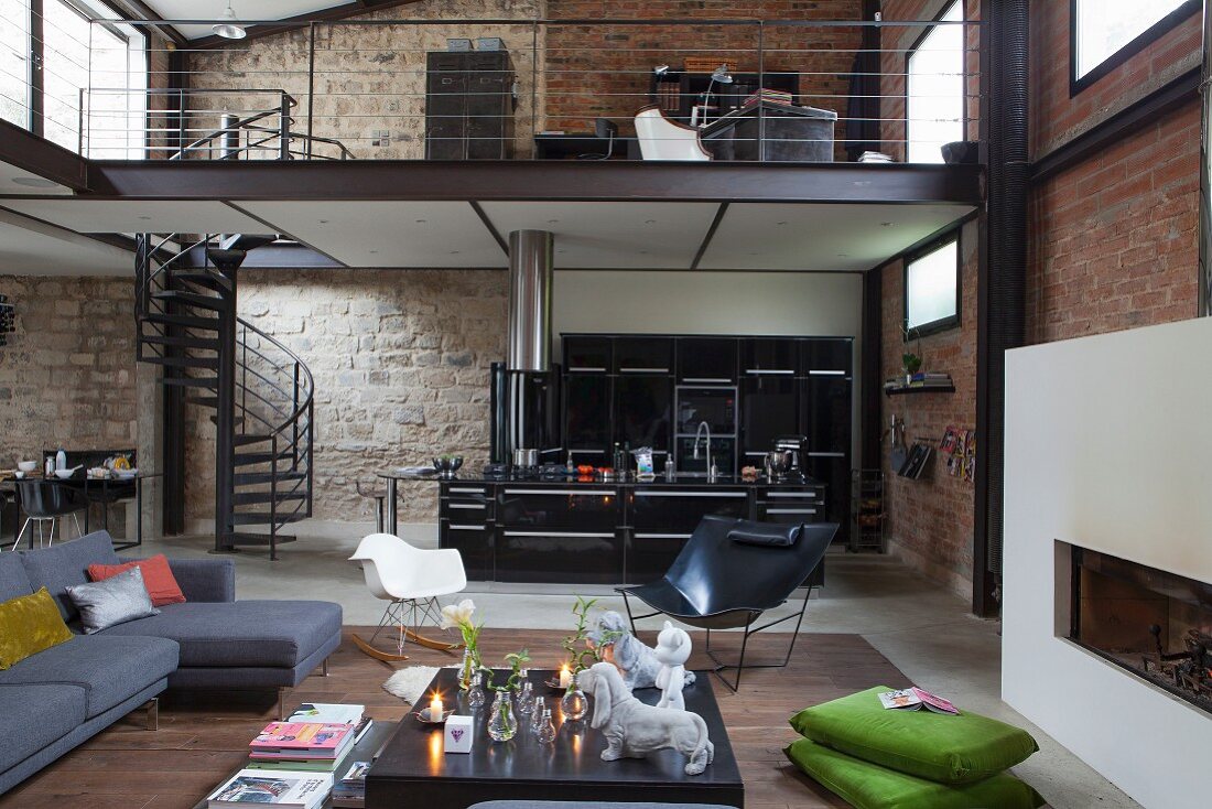 Lounge area and open-plan kitchen in loft apartment with brick and stone walls and view of gallery