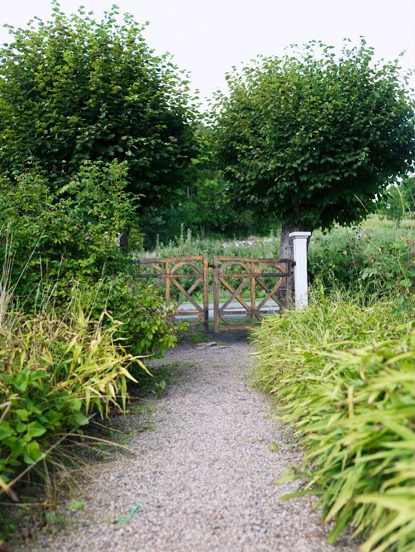 Gravel path in garden and view of rustic garden gate
