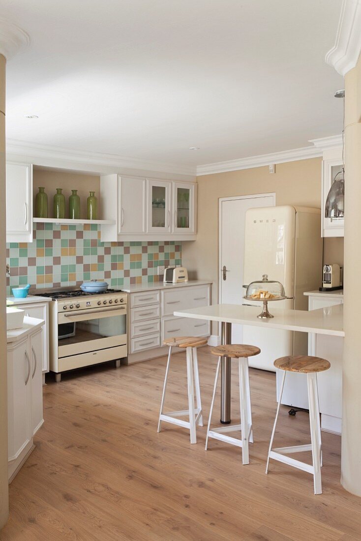 weiße Einbauküche mit Mosaikfliesenrückwand, Retro-Herd, Retro-Kühlschrank & Frühstückstheke mit Barhockern