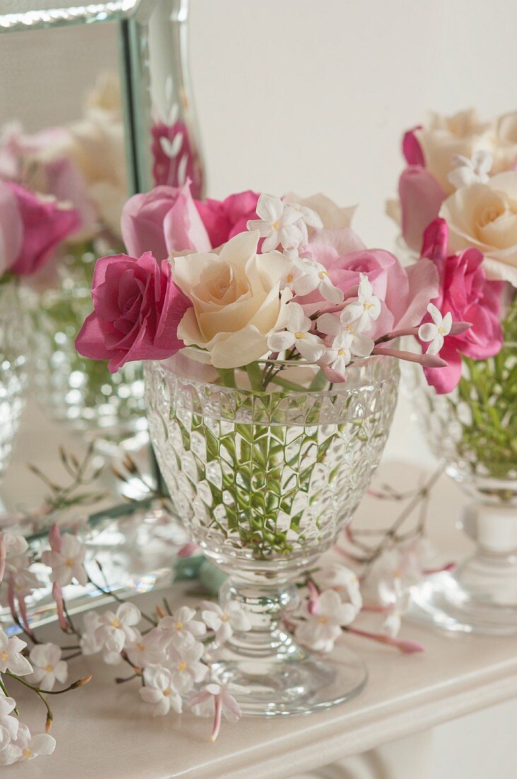 Pink and white roses with jasmine flowers in a glass