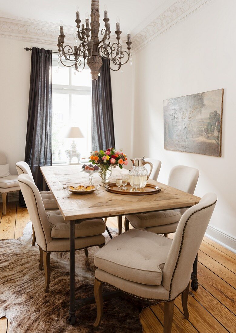 Chairs with beige upholstery at rustic dining table below chandelier in corner of traditional living room