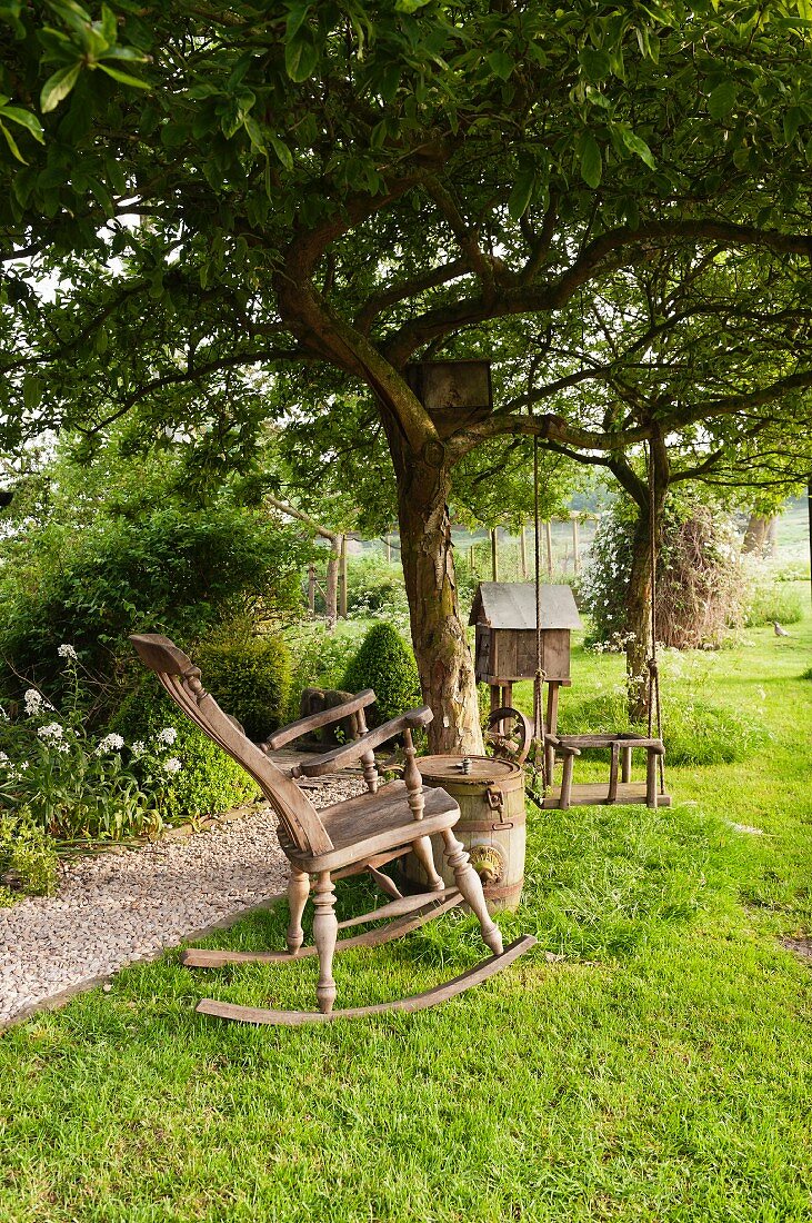 Vintage rocking chair under tree in idyllic garden