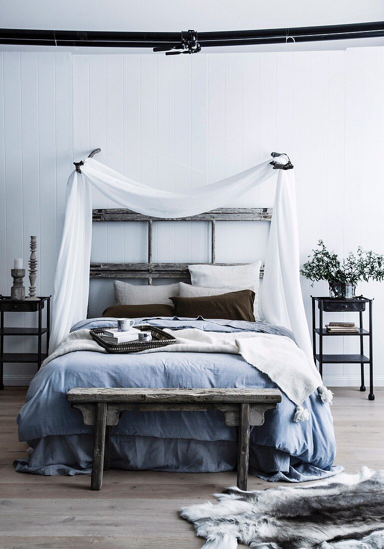 Rustikales Bett mit Baldachin aus weißem Stoff, ehemalige Türrahmen als Bettkopfteil