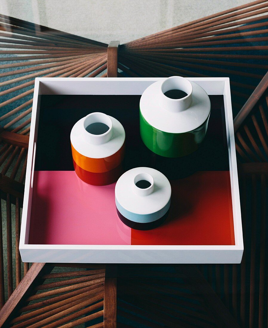 Vasen und Tablett in Retrofarben auf Glastisch mit kunsthandwerklichem Holzgestell