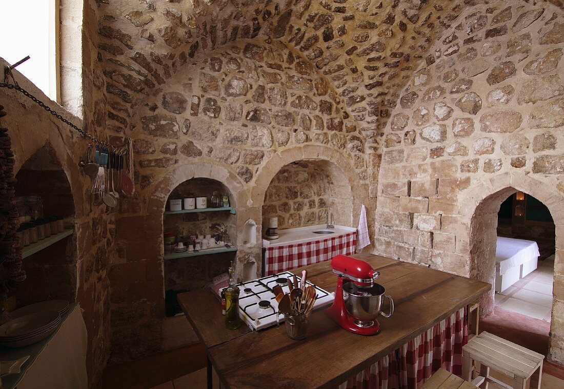 Kücheninsel mit Gaskochfeld in Holz Arbeitsplatte, in offener Küche eines historischen Wohnhauses mit Gewölbe und Mauern aus Kalkstein