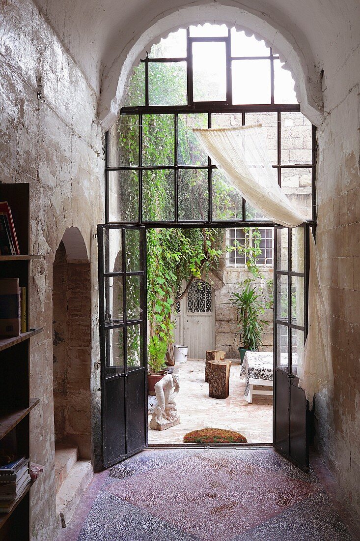 Vorraum mit hoher Rundbogentür aus Stahl und Glas, Blick in Innenhof eines historischen Wohnhauses