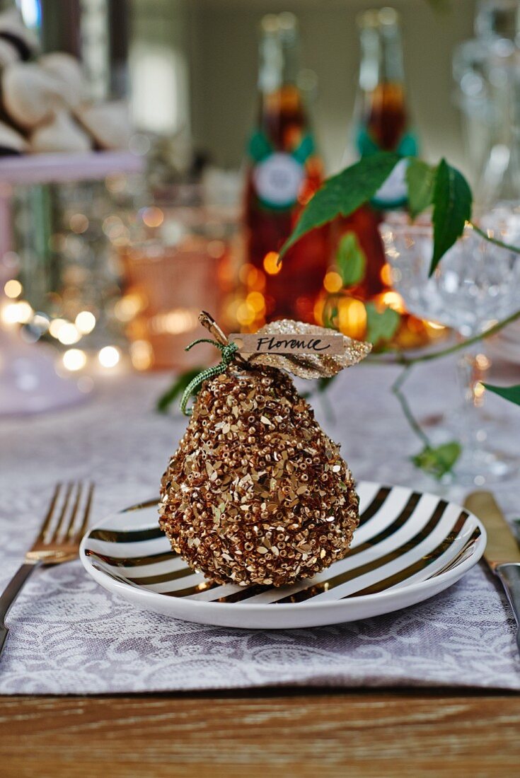 Dekorierte Birne mit Namensschildchen als weihnachtliche Tischdeko auf Schwarzweiss-Teller