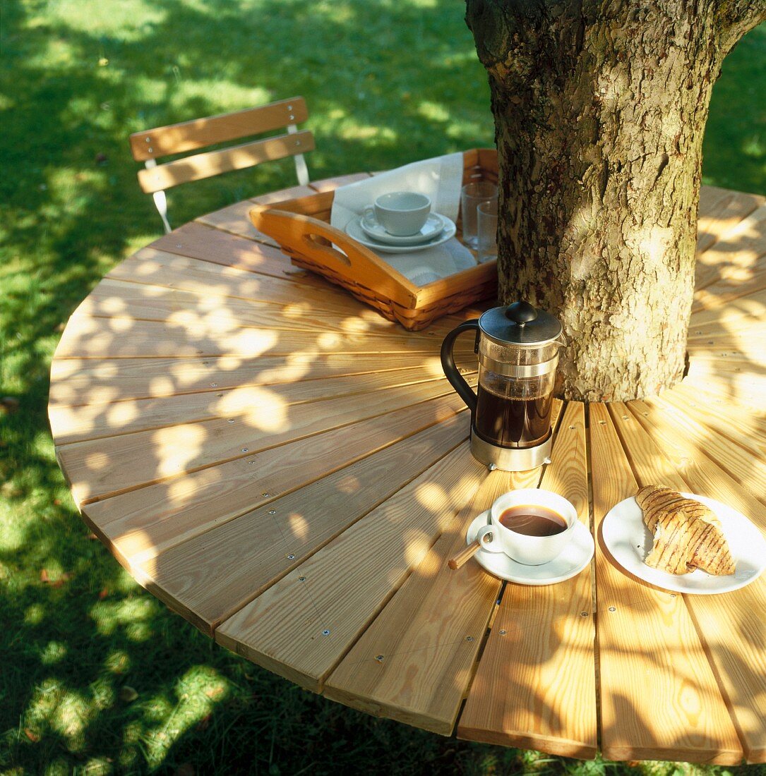 Selbstgebauter Gartentisch aus Lärchenholz, rund um einen Baumstamm