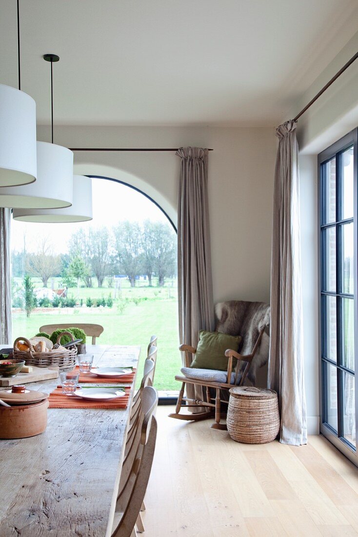 Ländliches Esszimmer mit bodentiefen Fenstern und Blick in den Garten