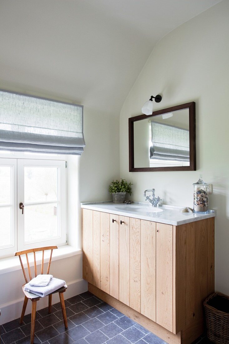 Washstand with wooden base unit and marble counter in attic bathroom
