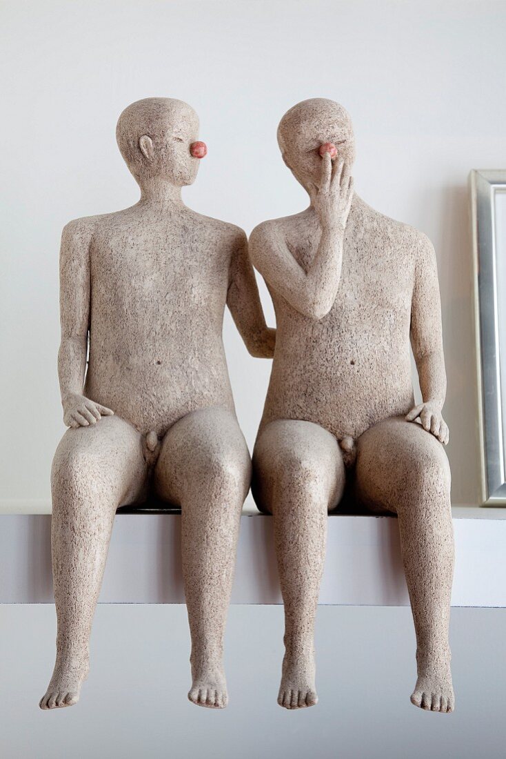 Two stone male sculptures sitting on shelf