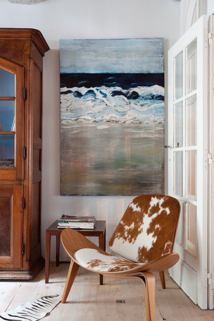 Classic easy chair with cowhide cover in corner next to lattice door and in front of painting on wall
