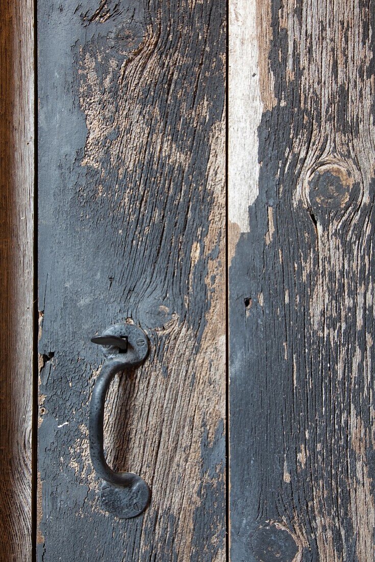 Schmiedeeiserner Griff an Holztür mit abblätternder Farbe