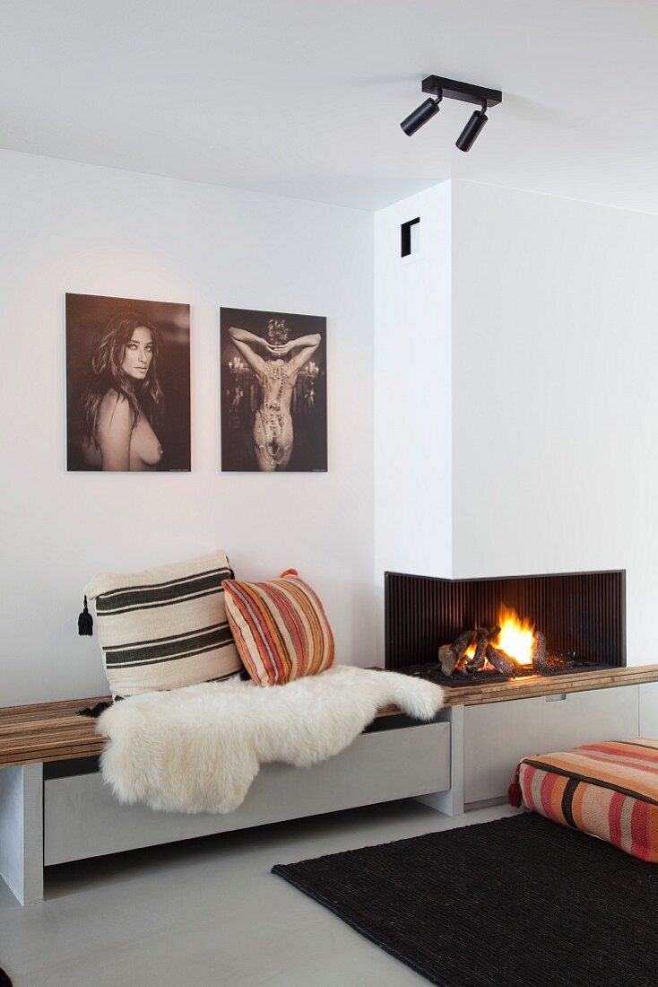 Sheepskin and cushions on custom bench below photographic artworks next to fireplace