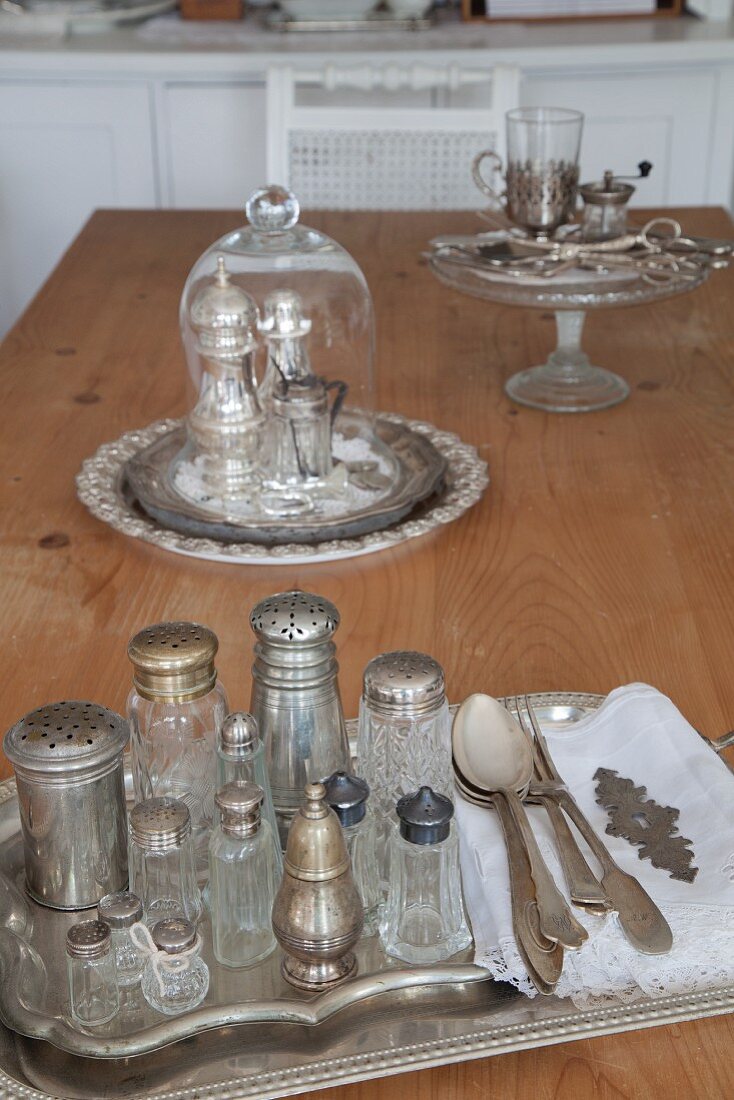 Vintage Salzstreuer auf Silber Tablett und Glashaube über Salz- und Pfefferstreuer im Hintergrund auf Holztisch
