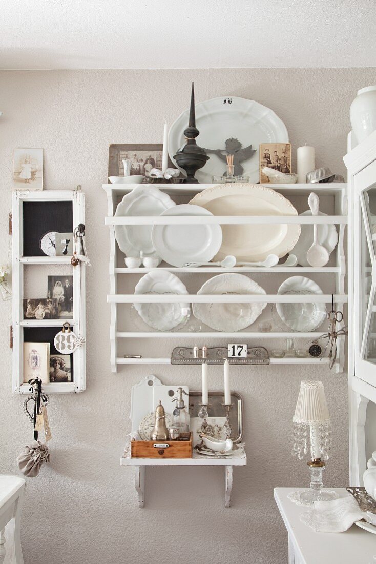 White decorative plates and platters in plate rack on pastel wall in rustic kitchen