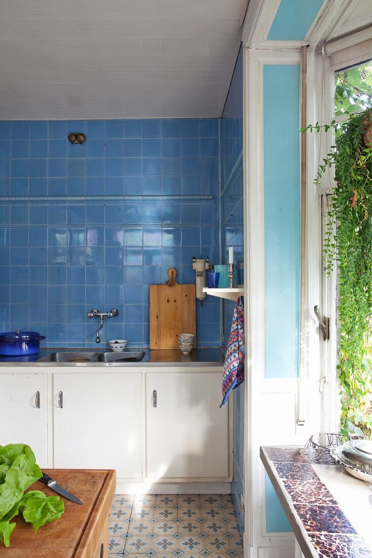 Küchenzeile mit weissen Unterschränken vor blau gefliester Wand