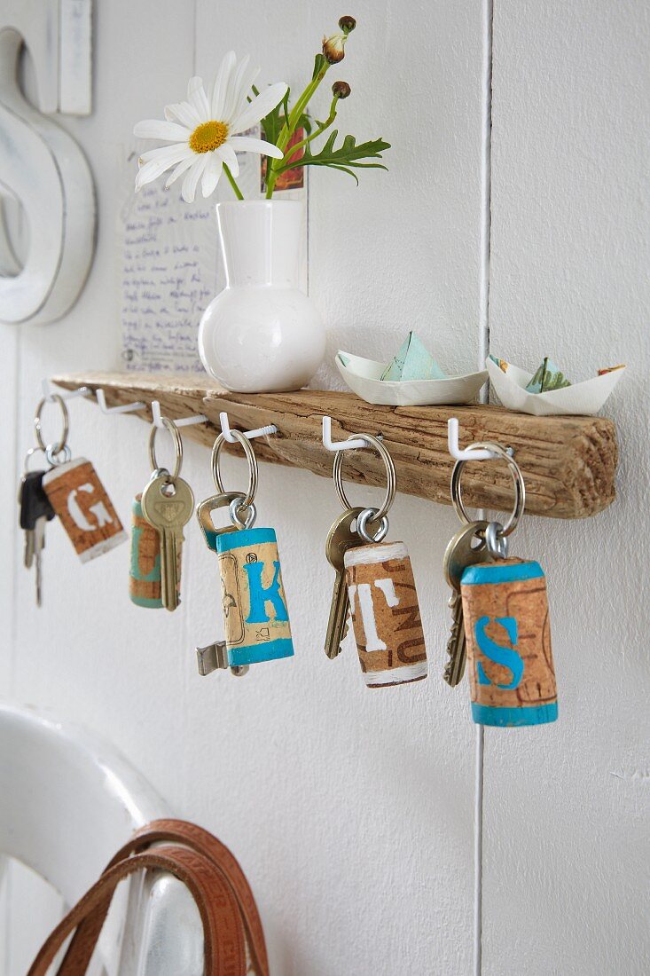 A key board made from driftwood and keys with homemade key rings made from corks painted with letters