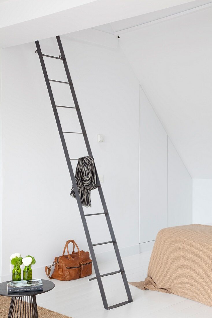 Filigrane, moderne Metallleiter an Wand in minimalistischem Schlafzimmer unter dem Dach