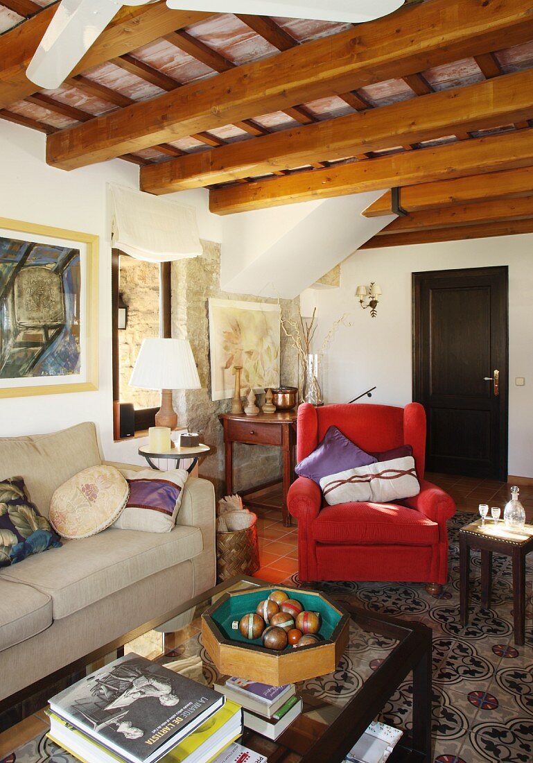 Traditional living room in stone house with exposed wooden roof structure; boccia balls on coffee table