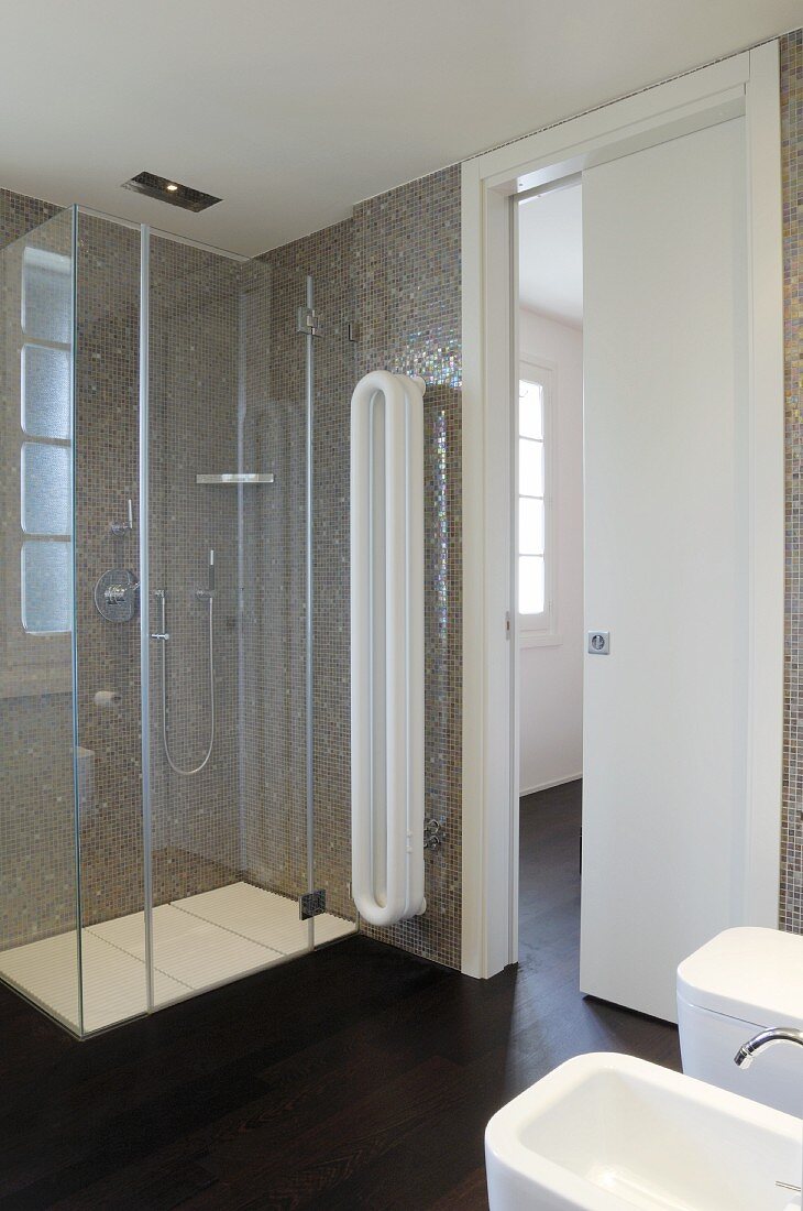 Modernes Bad mit weissen Sanitärobjekten, gegenüber Glas Duschkabine vor gefliesten Wänden