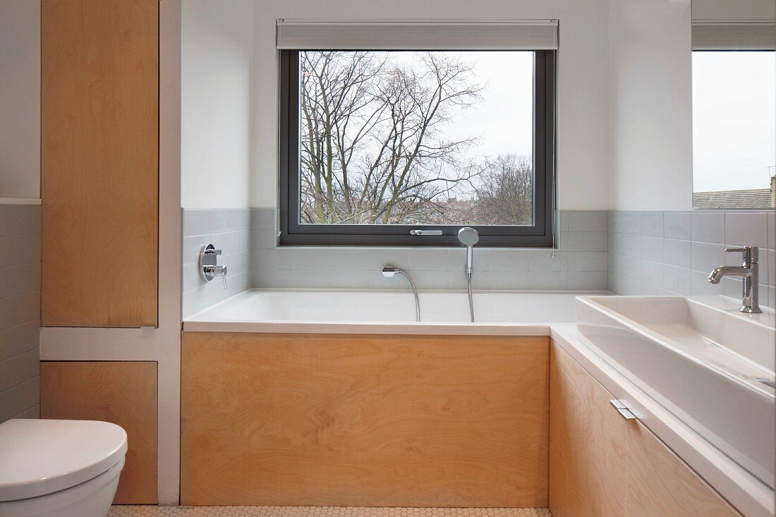Bathroom with custom wooden elements and bathtub below window
