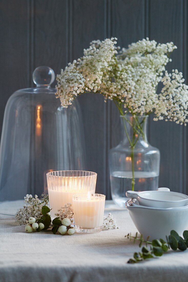 Festlich gedeckter Tisch mit Kerzen, Blumenvase, Cloche und Schälchen